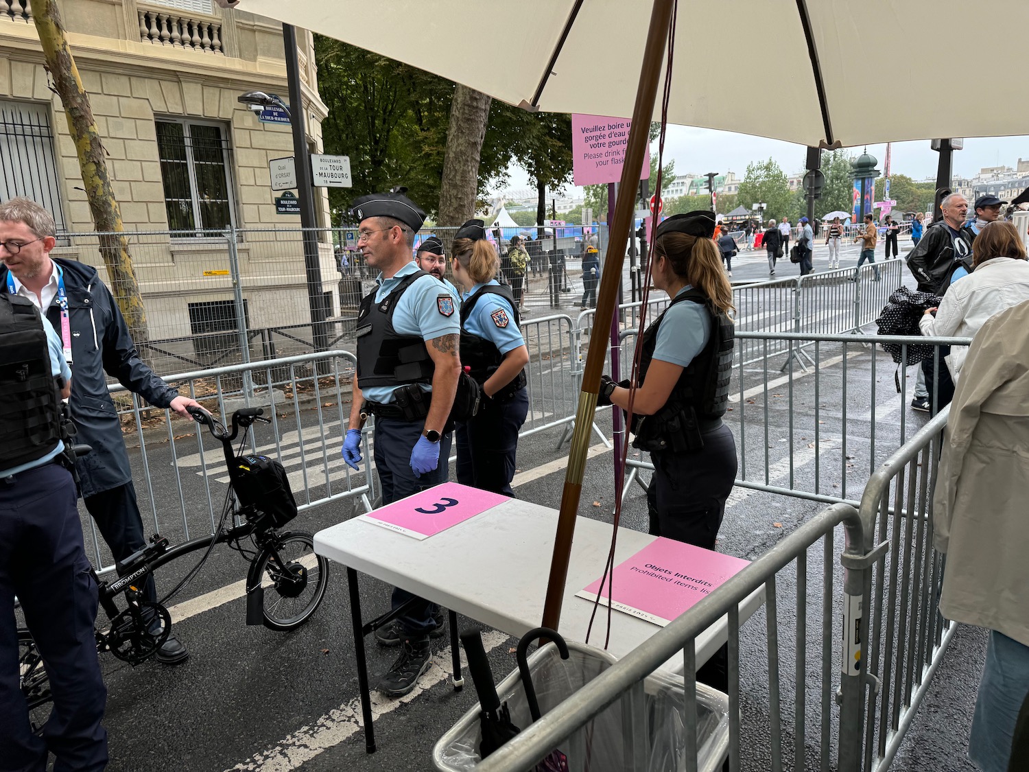 a group of people standing under a white table with pink signs