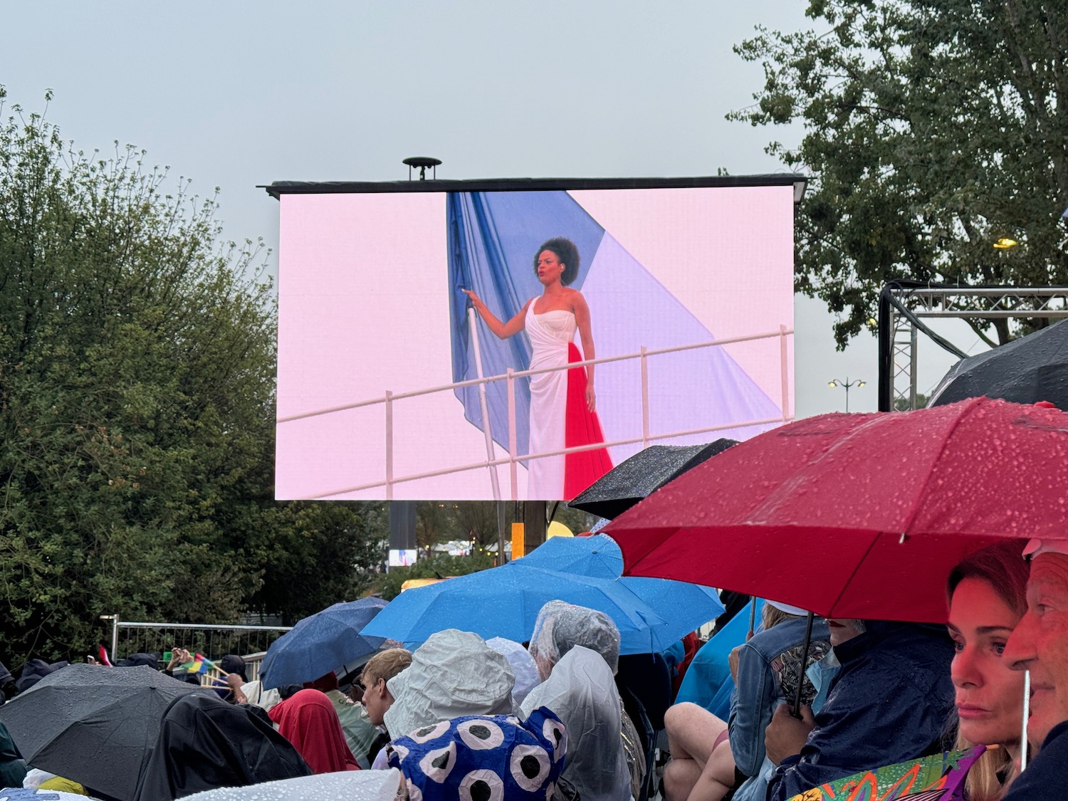 a woman in a white dress standing on a stage with a large screen