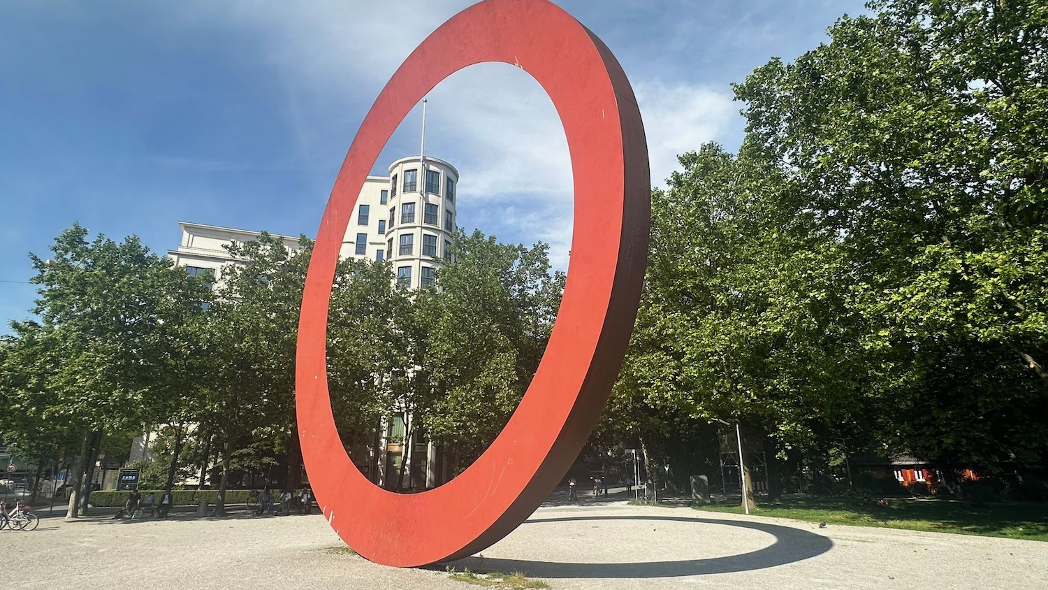 a large red circle sculpture in a park