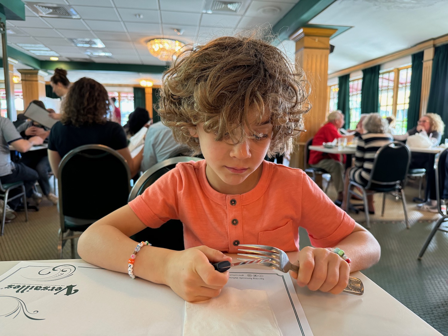 a child sitting at a table with a fork