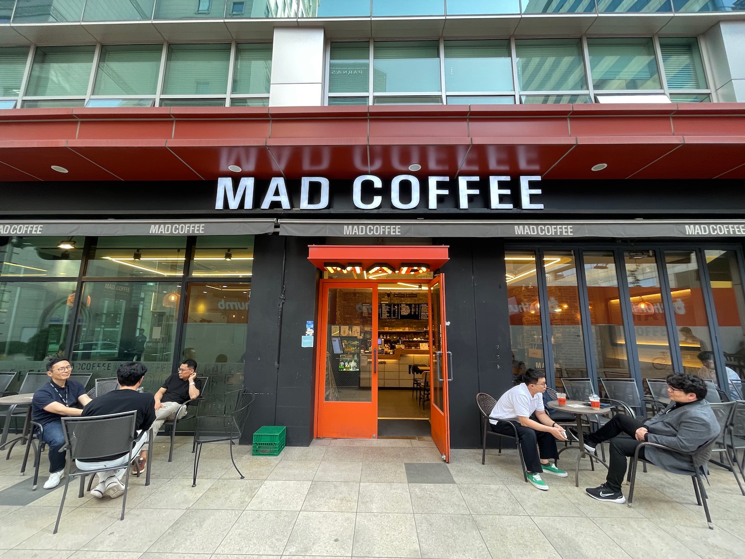 a group of people sitting outside of a coffee shop