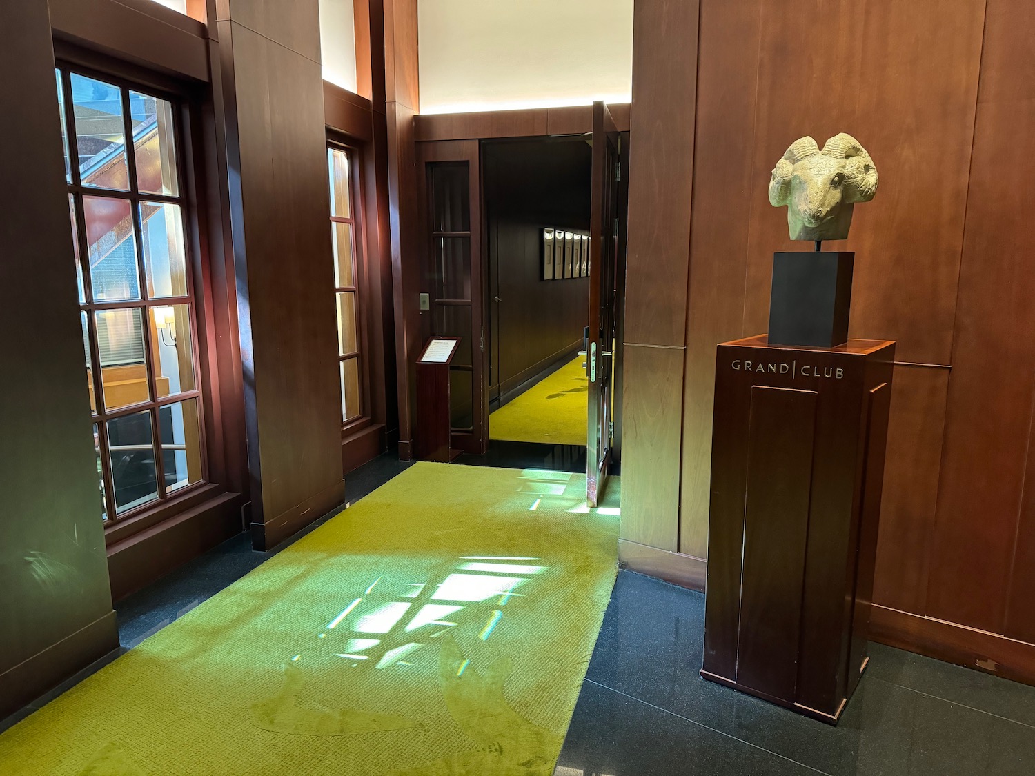 a hallway with a statue of a goat head on a pedestal