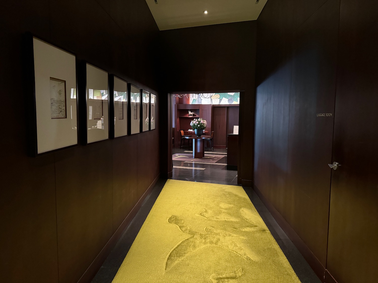 a hallway with a yellow carpet and pictures on the wall