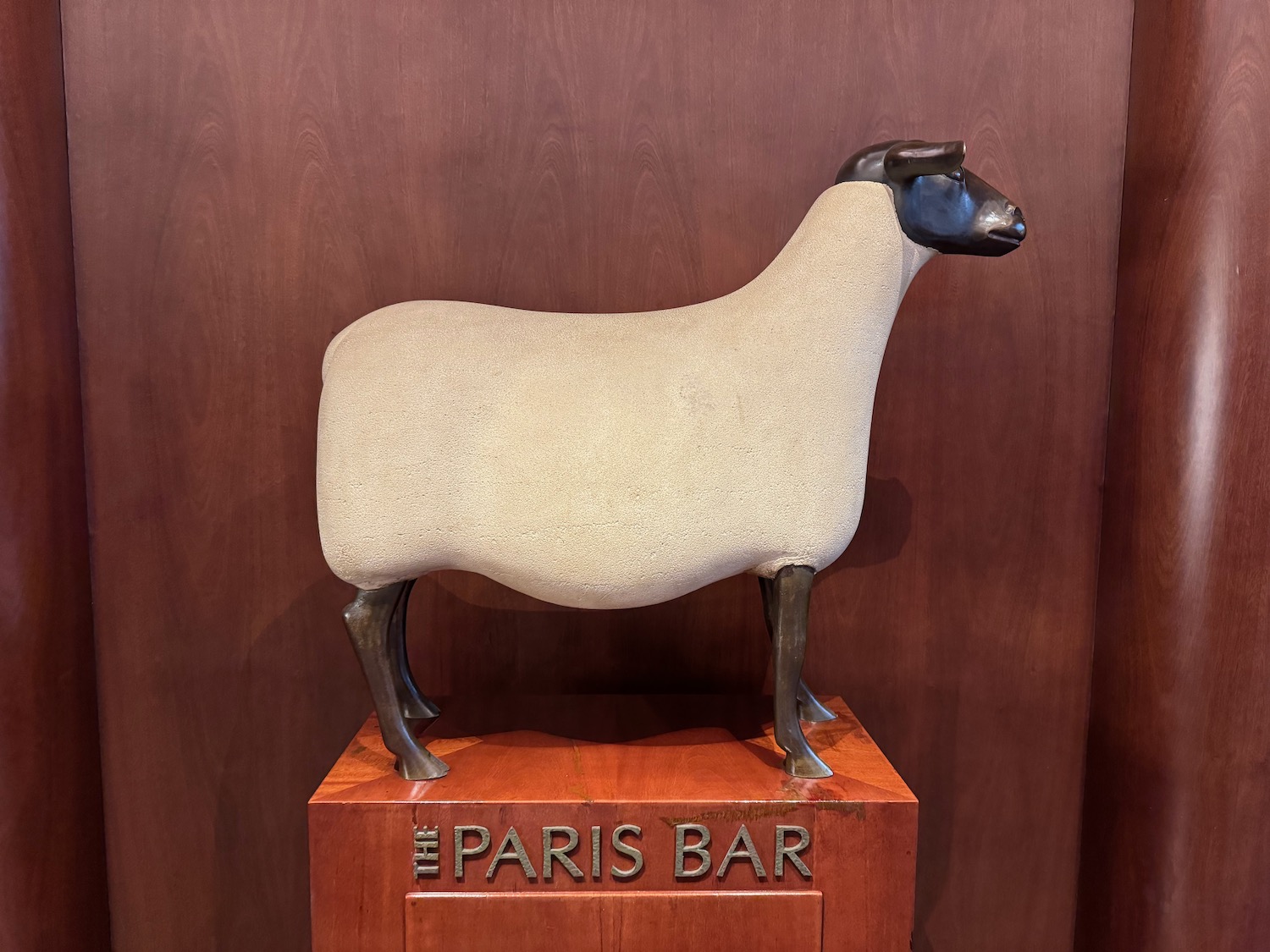 a statue of a sheep on a wooden stand