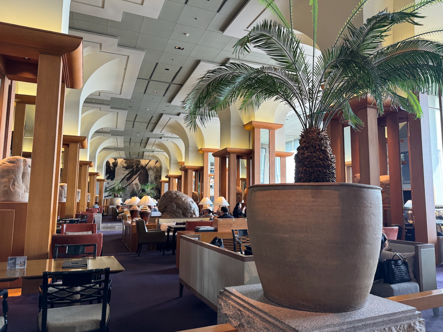 a room with a large potted plant and tables and chairs