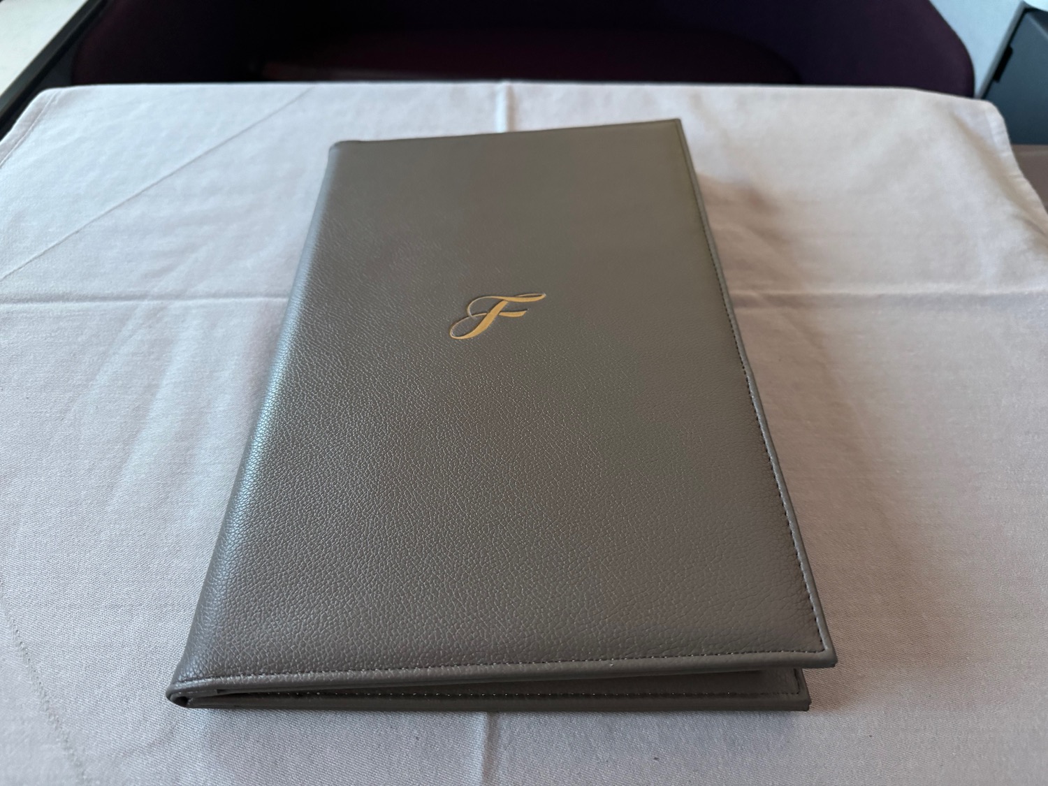 a grey leather menu cover on a white tablecloth