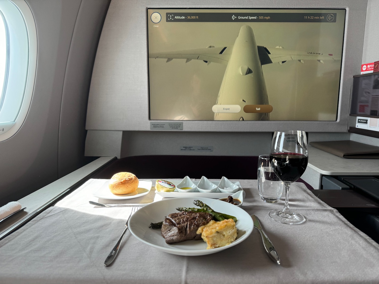 a plate of food and a glass of wine on a table in an airplane