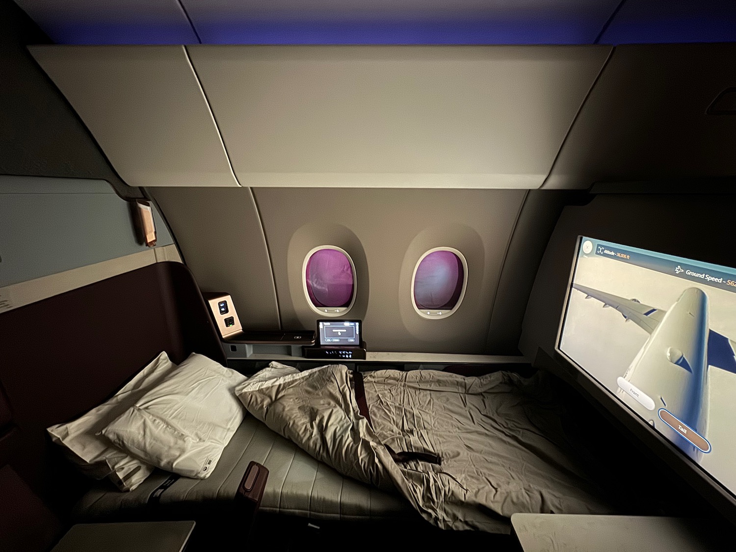 a bed with a screen and windows in an airplane