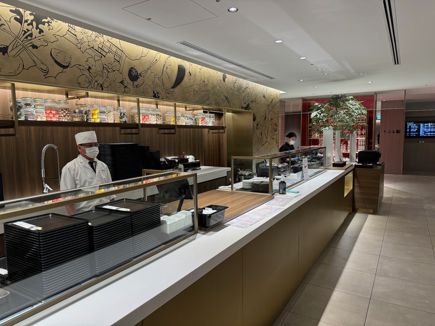 a man wearing a mask behind a counter in a restaurant