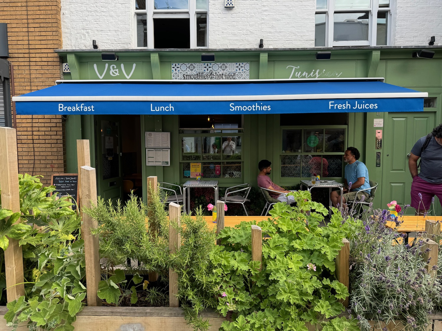 a two men sitting at a table outside a restaurant