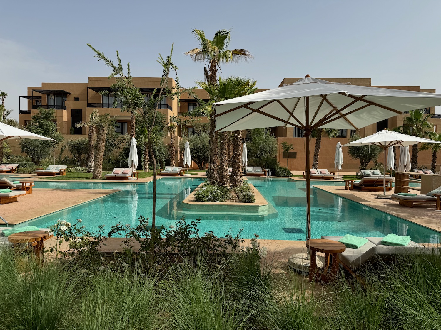 a pool with sun loungers and parasols in front of a building