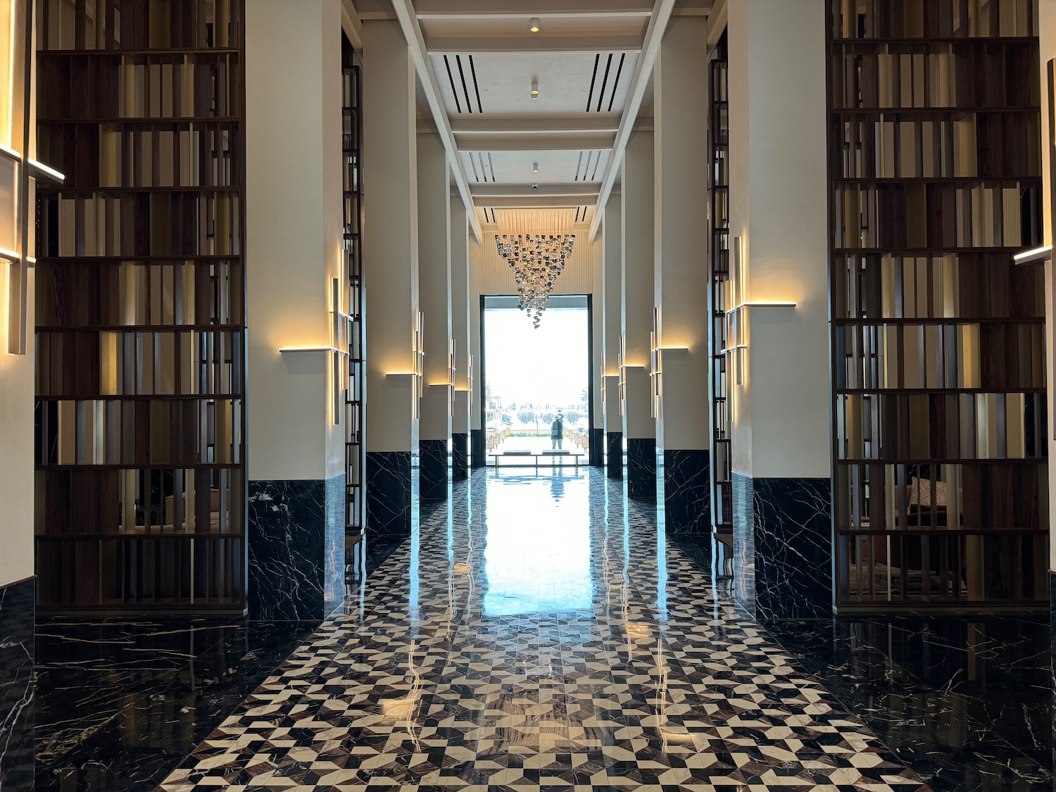 a hallway with bookshelves and chandelier