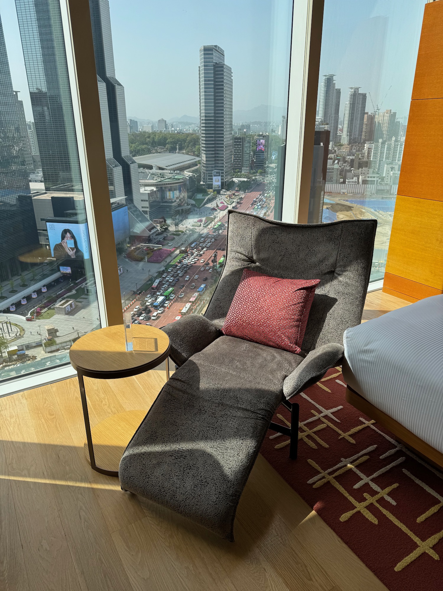 a chair with cushions and a table in front of a window