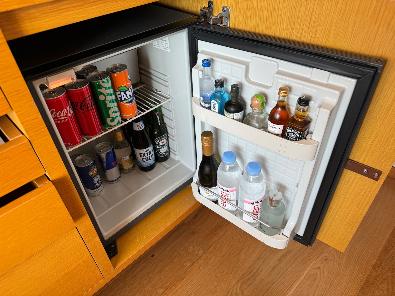 a mini fridge with bottles of soda and cans