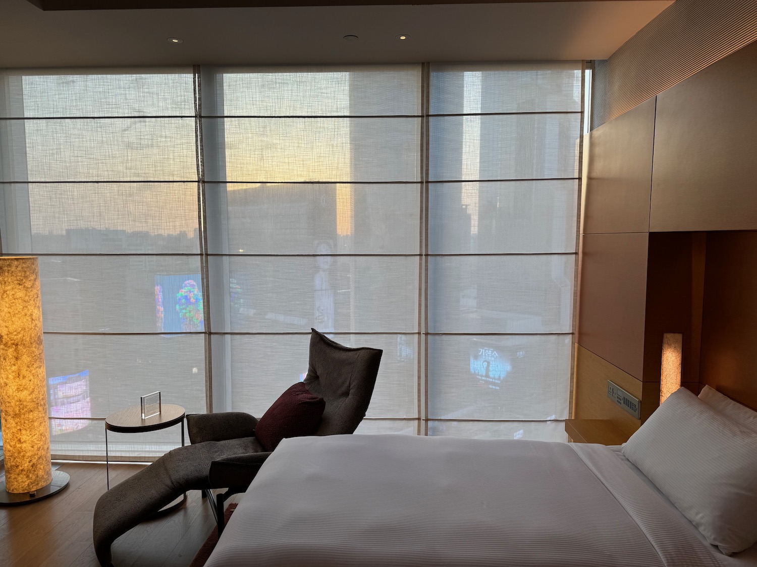 a bed with a chair in a room with large windows