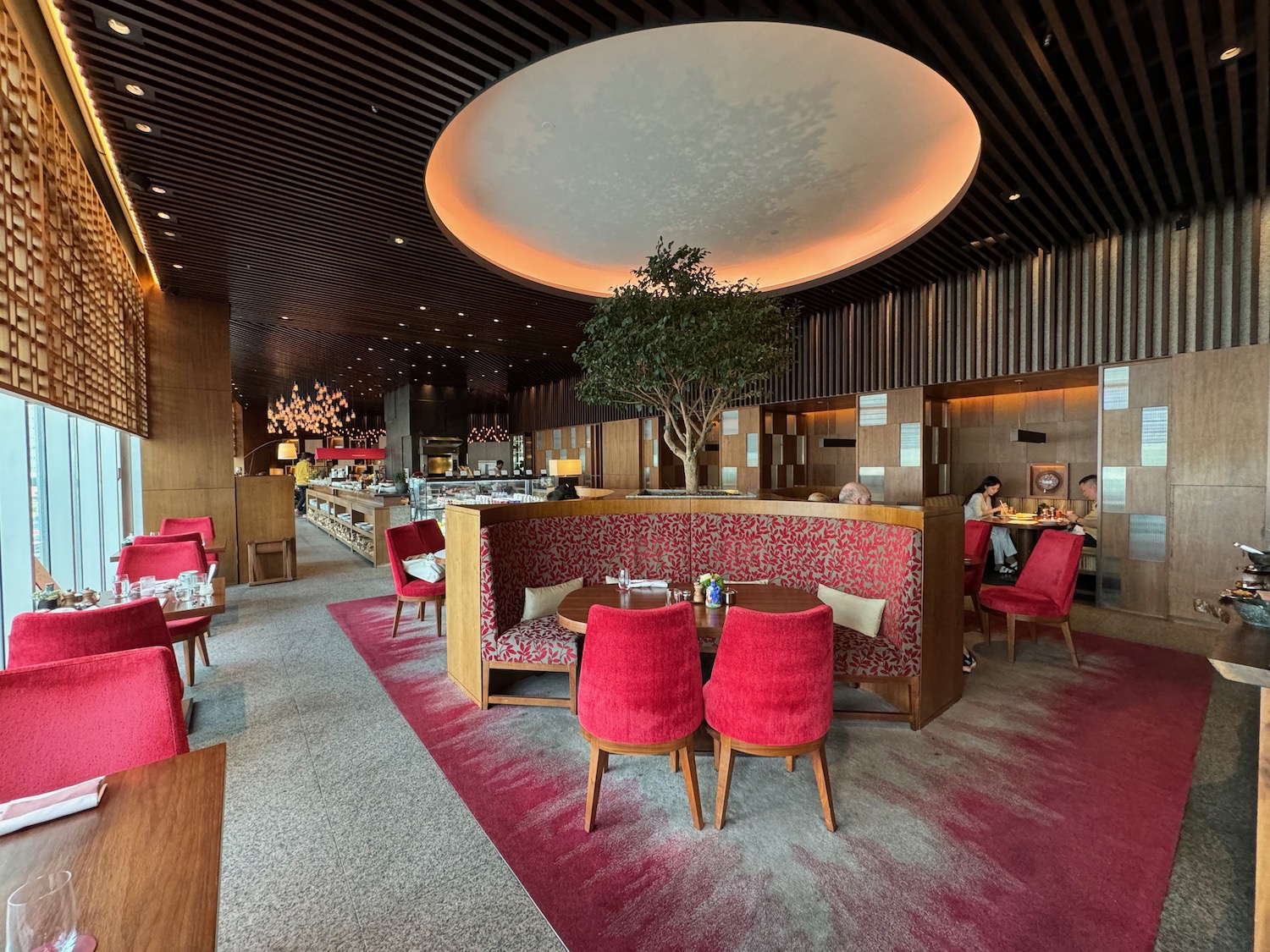 a restaurant with red chairs and a tree