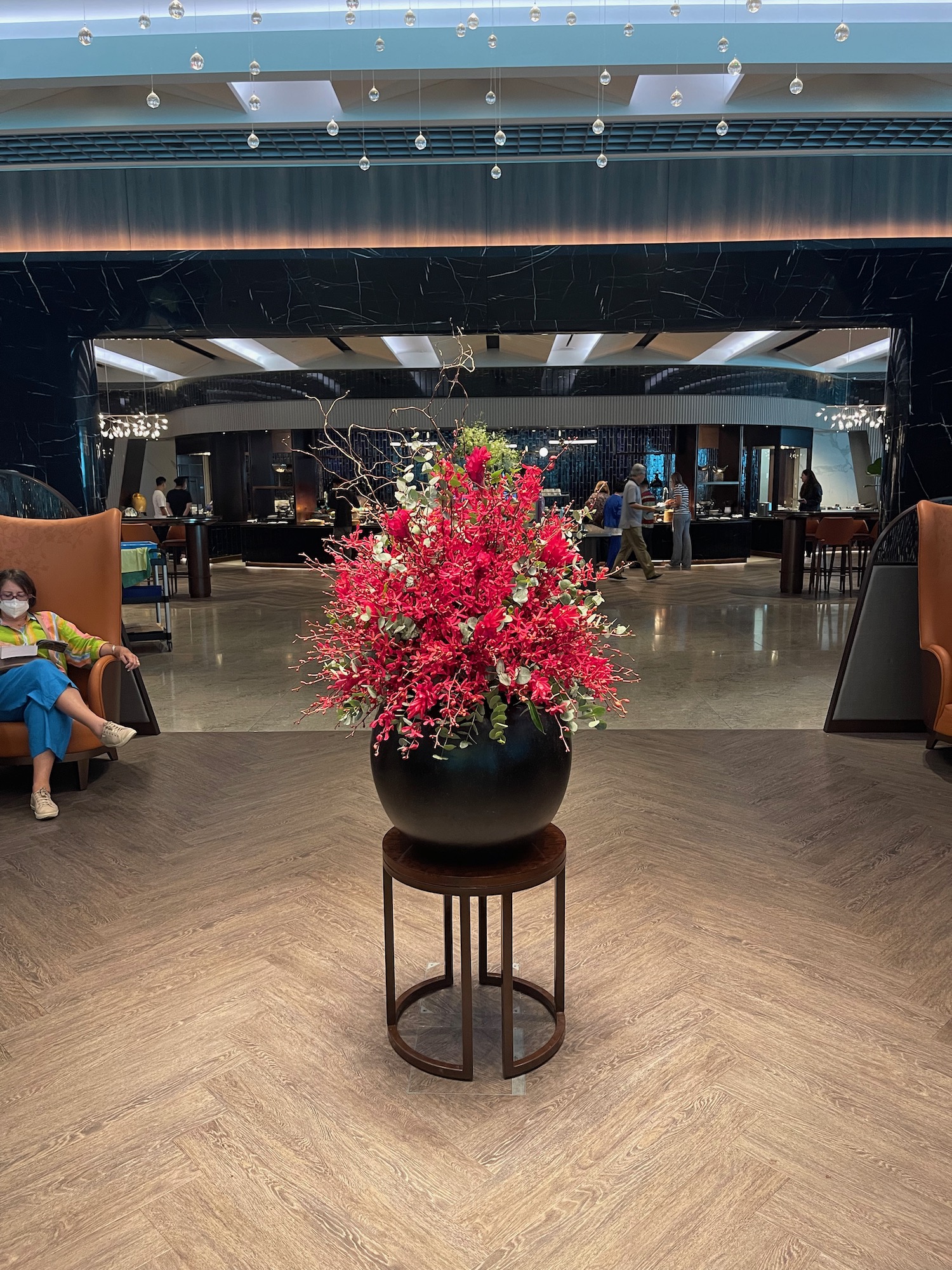 a large vase with flowers in front of a large mirror