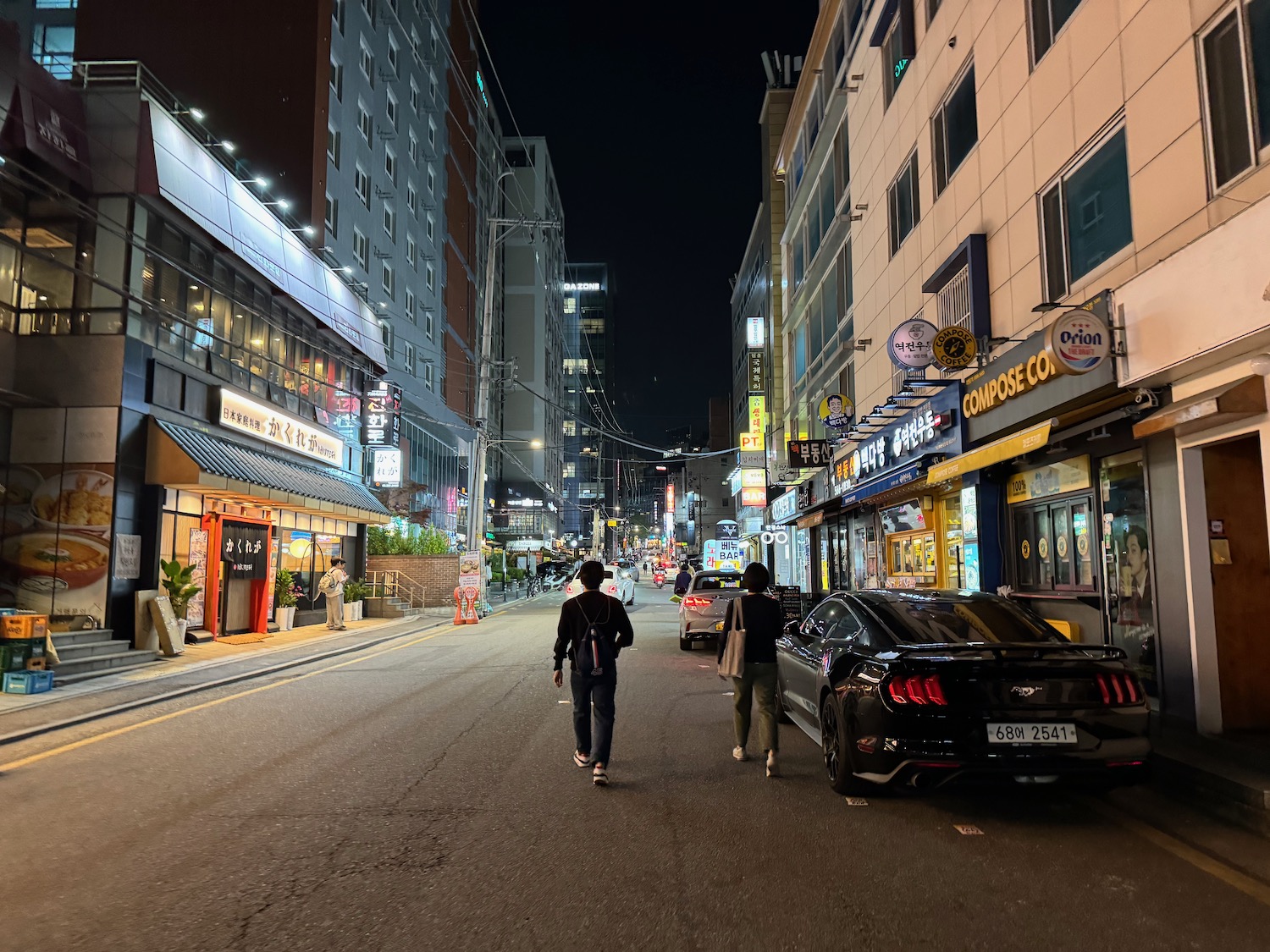 people walking down a street with cars and buildings