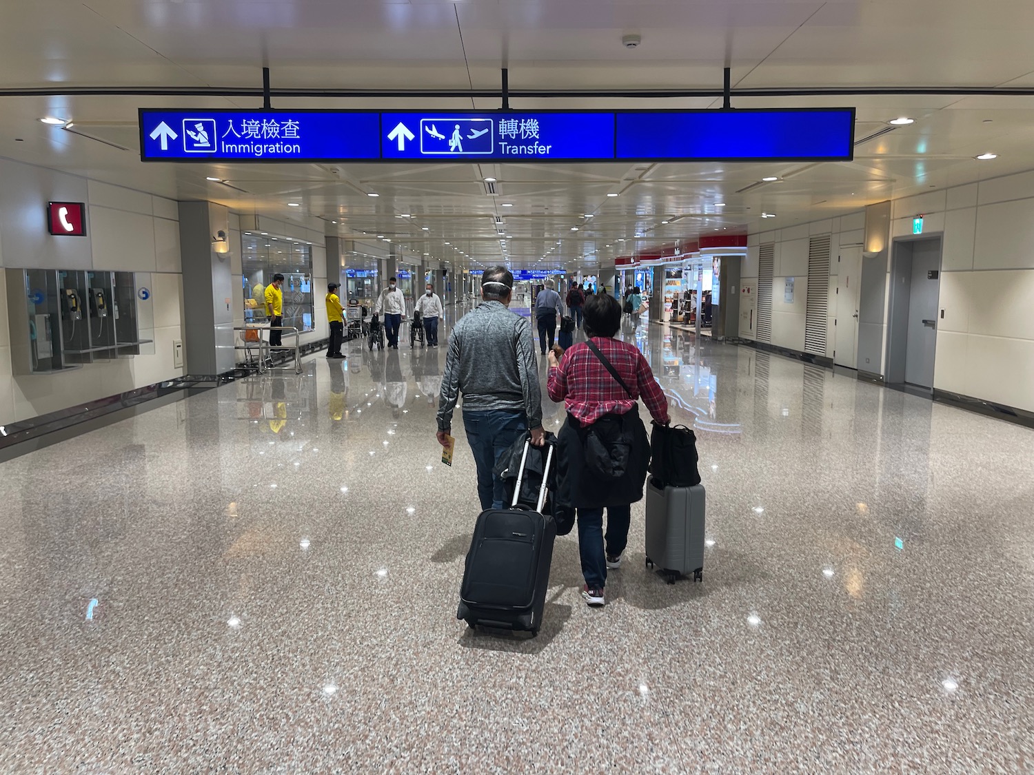 People walking through a hallway with luggage