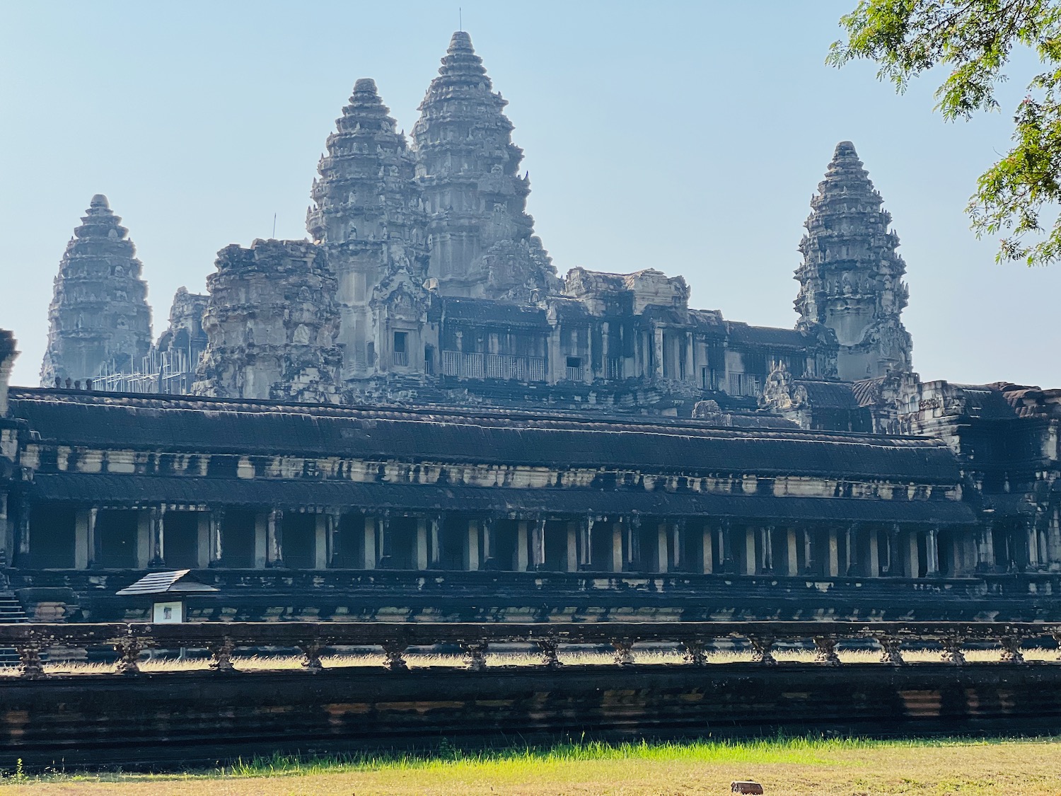 a large stone building with towers and columns with Angkor Wat in the background