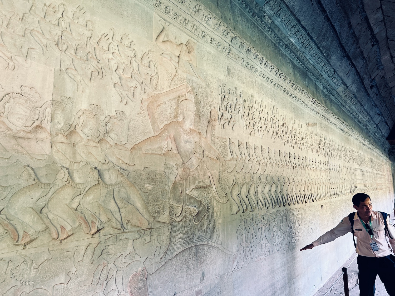 a person pointing at a stone wall with a group of people