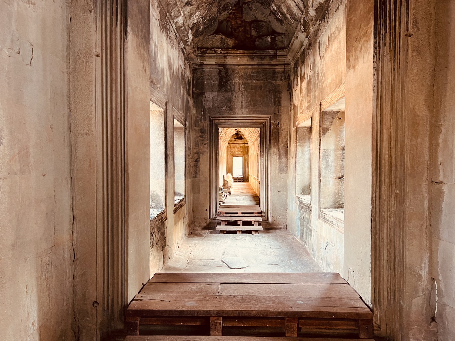 a long hallway with wooden benches and windows