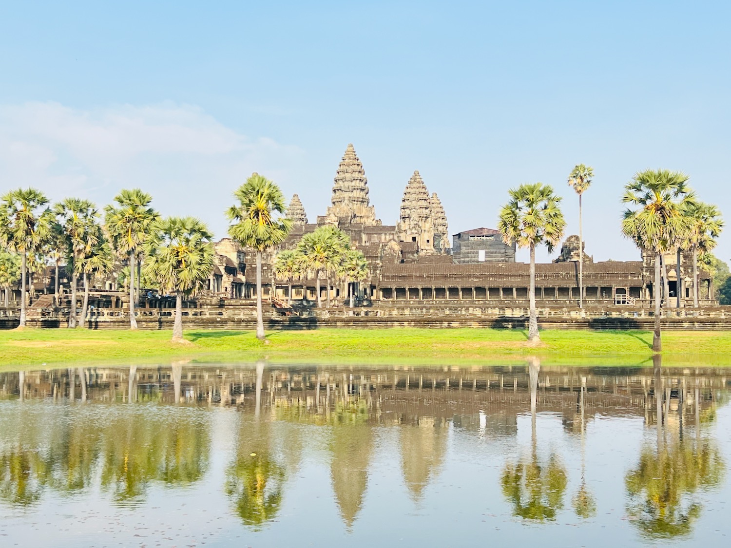 a body of water with Angkor Wat and palm trees