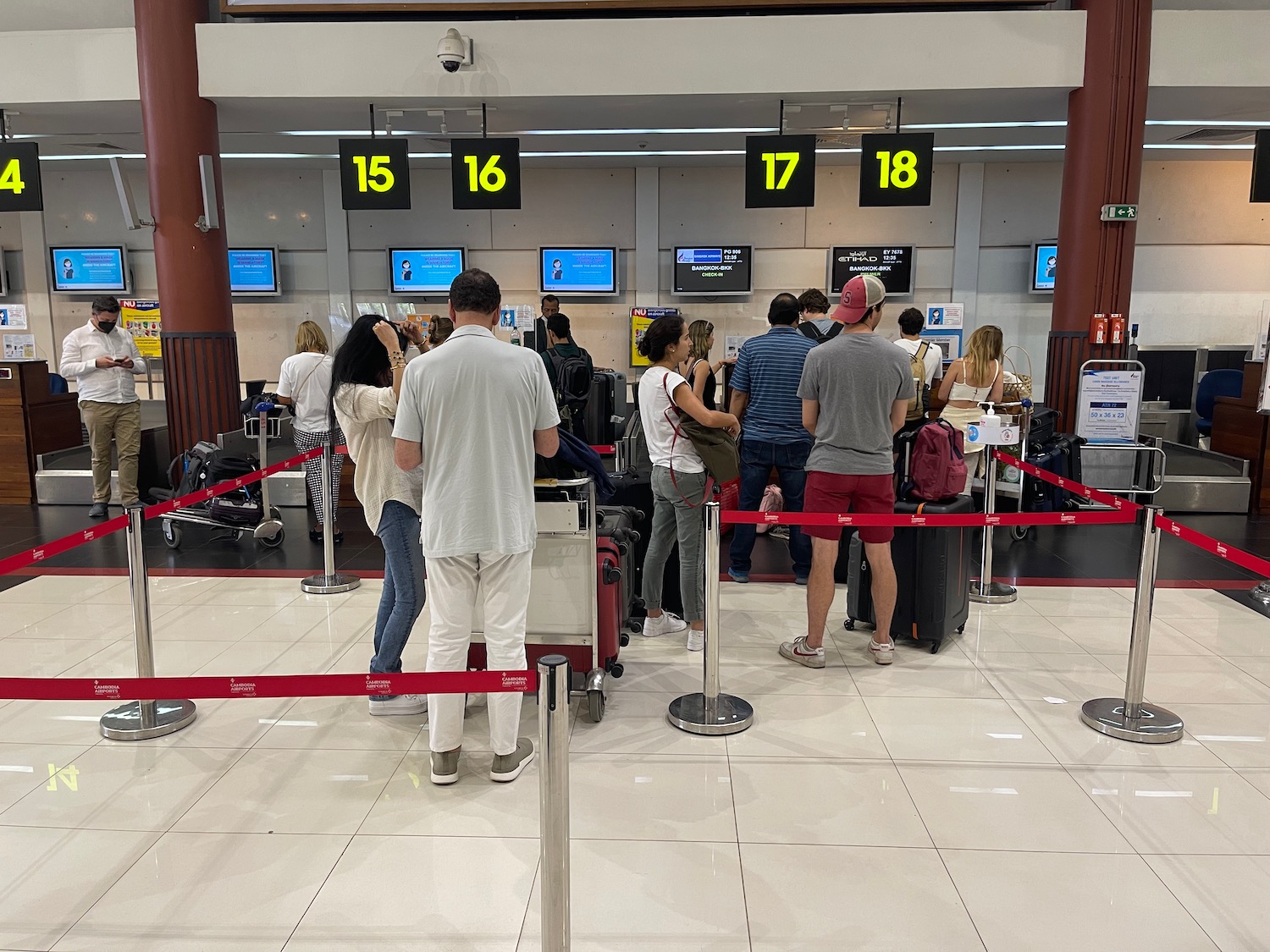 a group of people standing in line at an airport check in counter