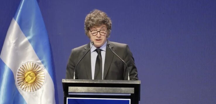 a man standing at a podium with microphones