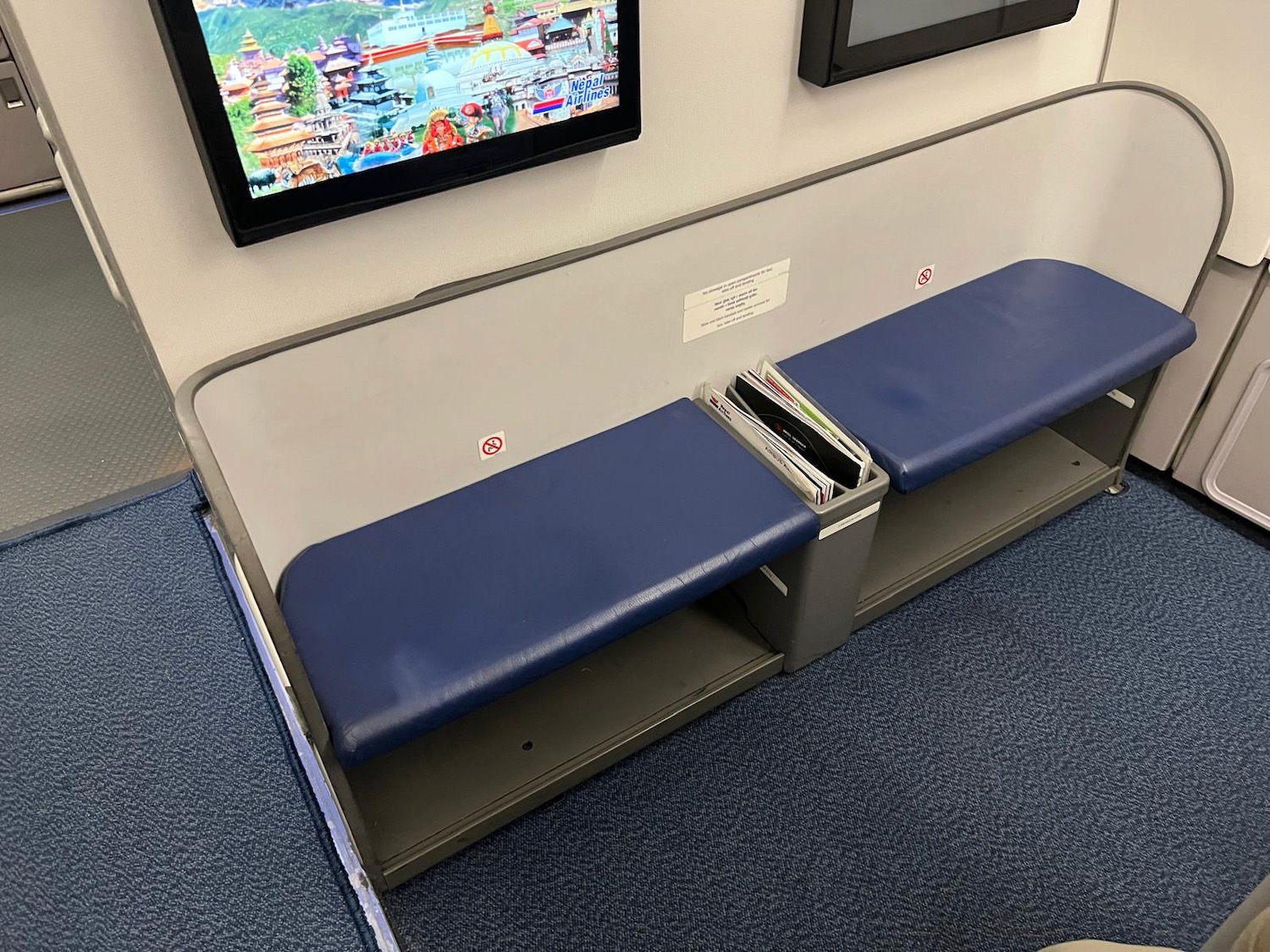 a bench with a blue seat and a black screen on the wall