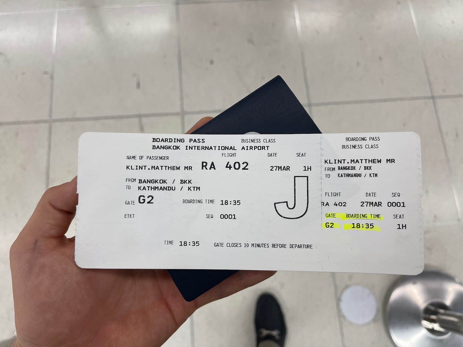 a hand holding a passport and boarding pass