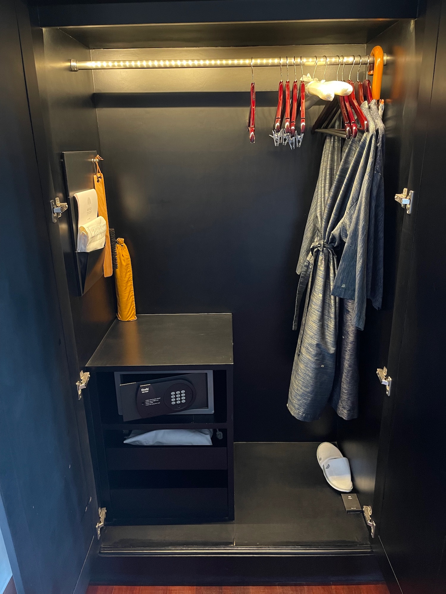 a black closet with a black shelf and a robe