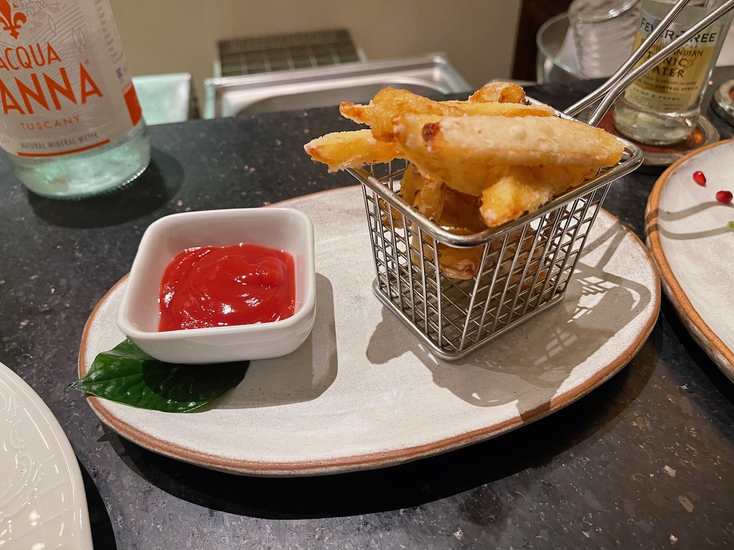 a small basket of french fries with ketchup on a plate