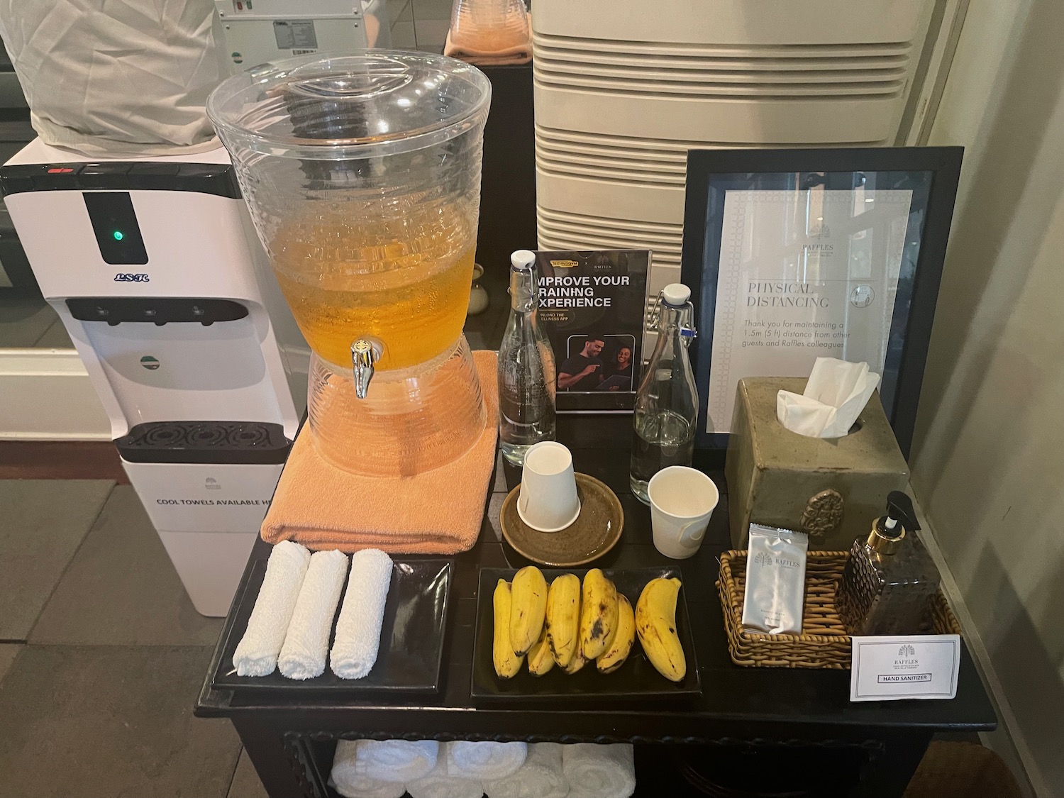 a table with a drink dispenser and bananas