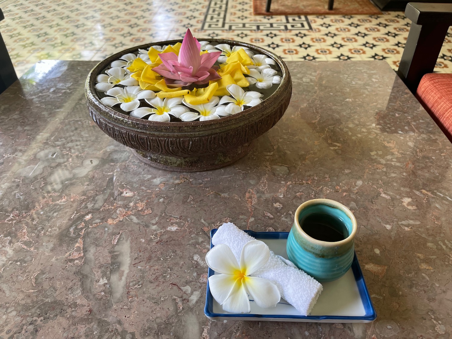 a bowl of water with flowers and a cup of coffee on a table