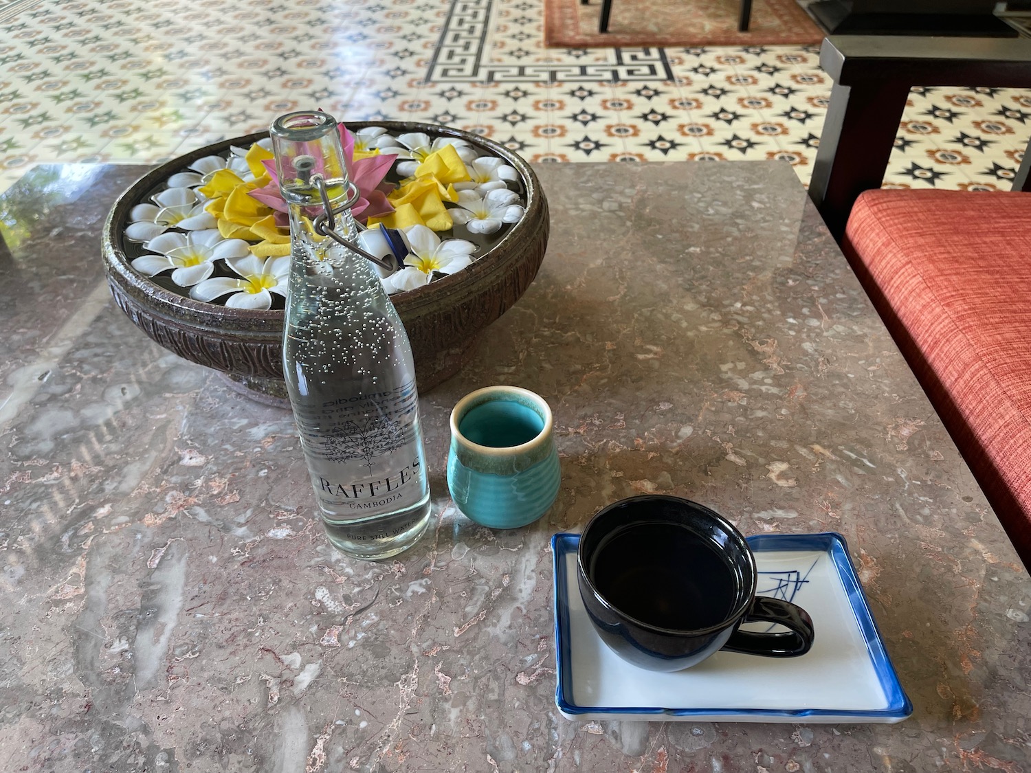 a bowl of flowers and a bottle of water on a table