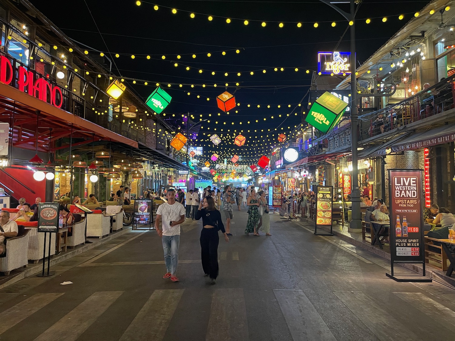 people walking on a street with colorful lights