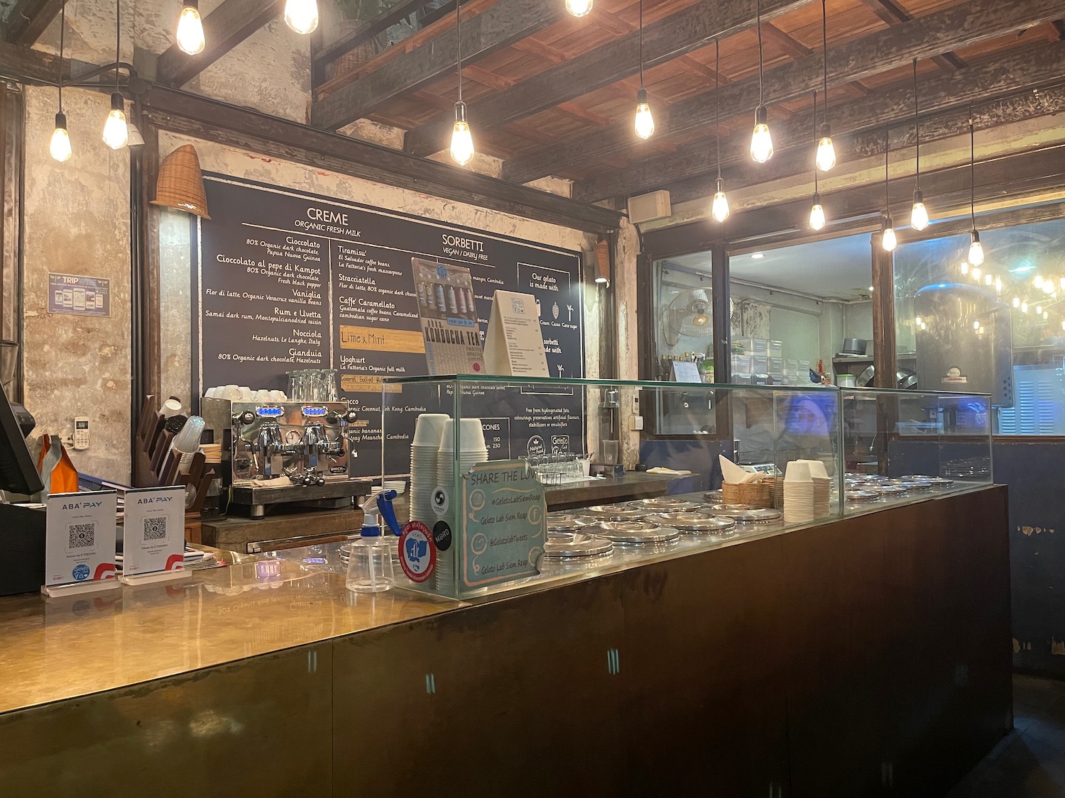 a counter with a glass case and a blackboard with writing on it