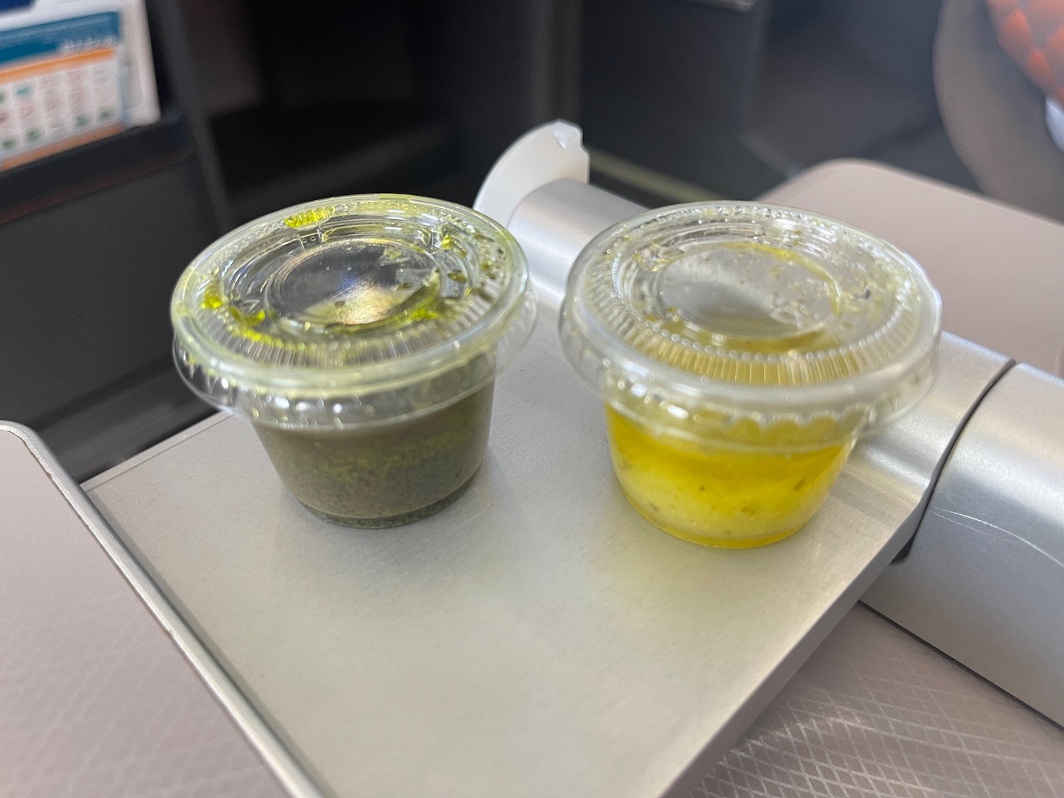 two plastic containers of sauce on a table