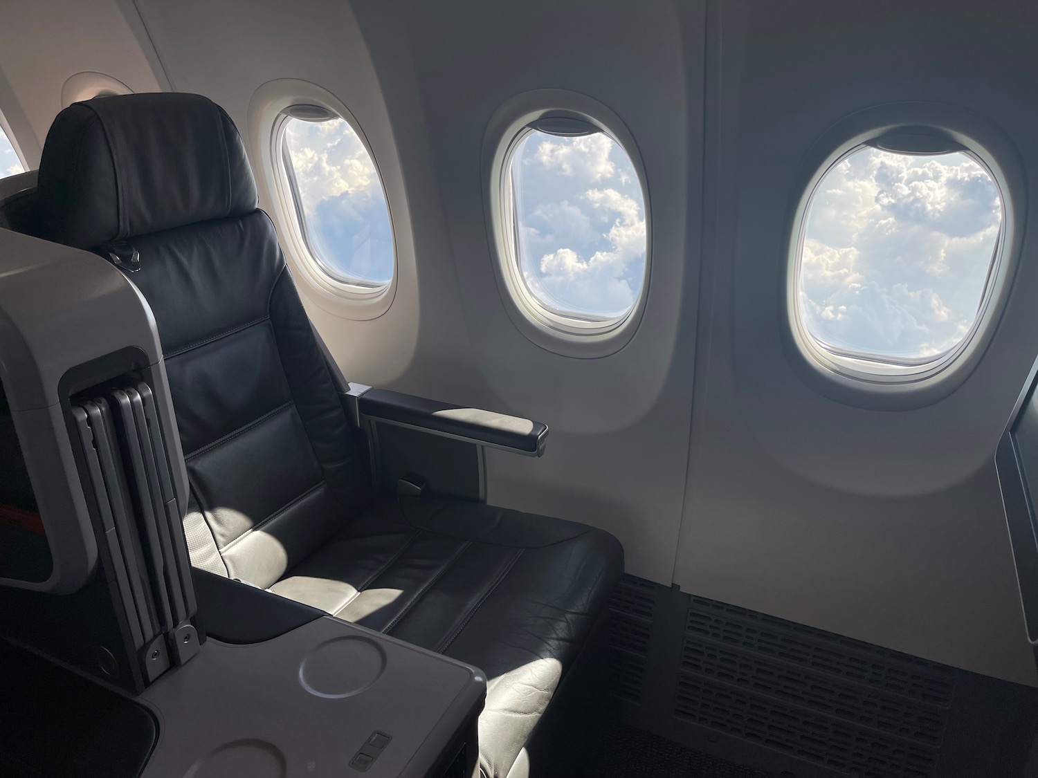 a seat in an airplane with windows and clouds in the sky