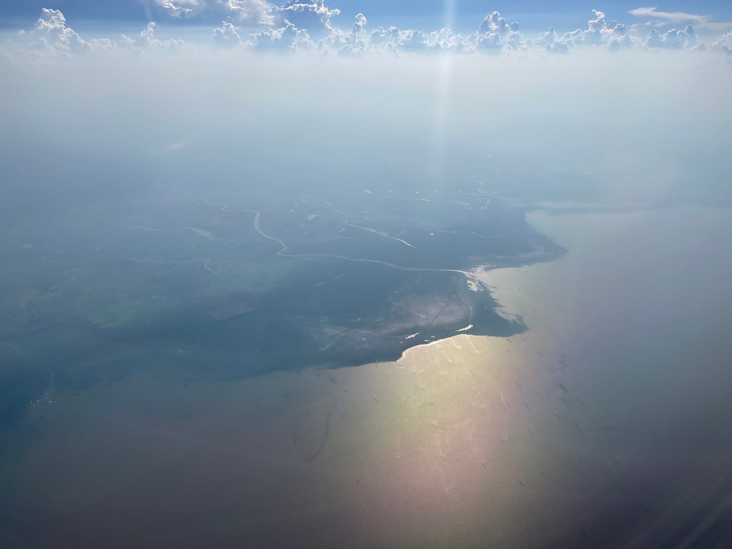 an aerial view of a land with clouds and blue sky