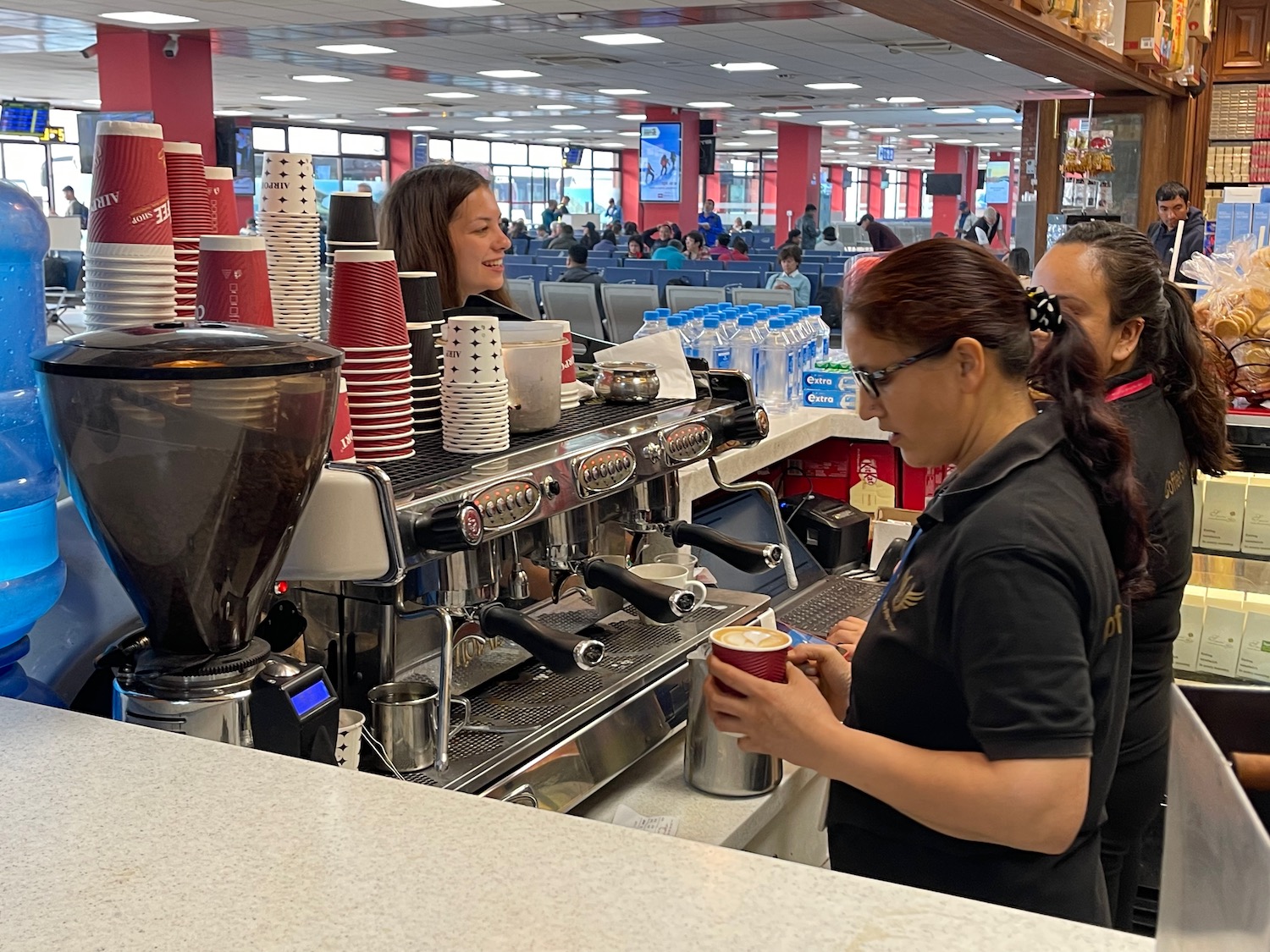 a woman standing behind a coffee machine