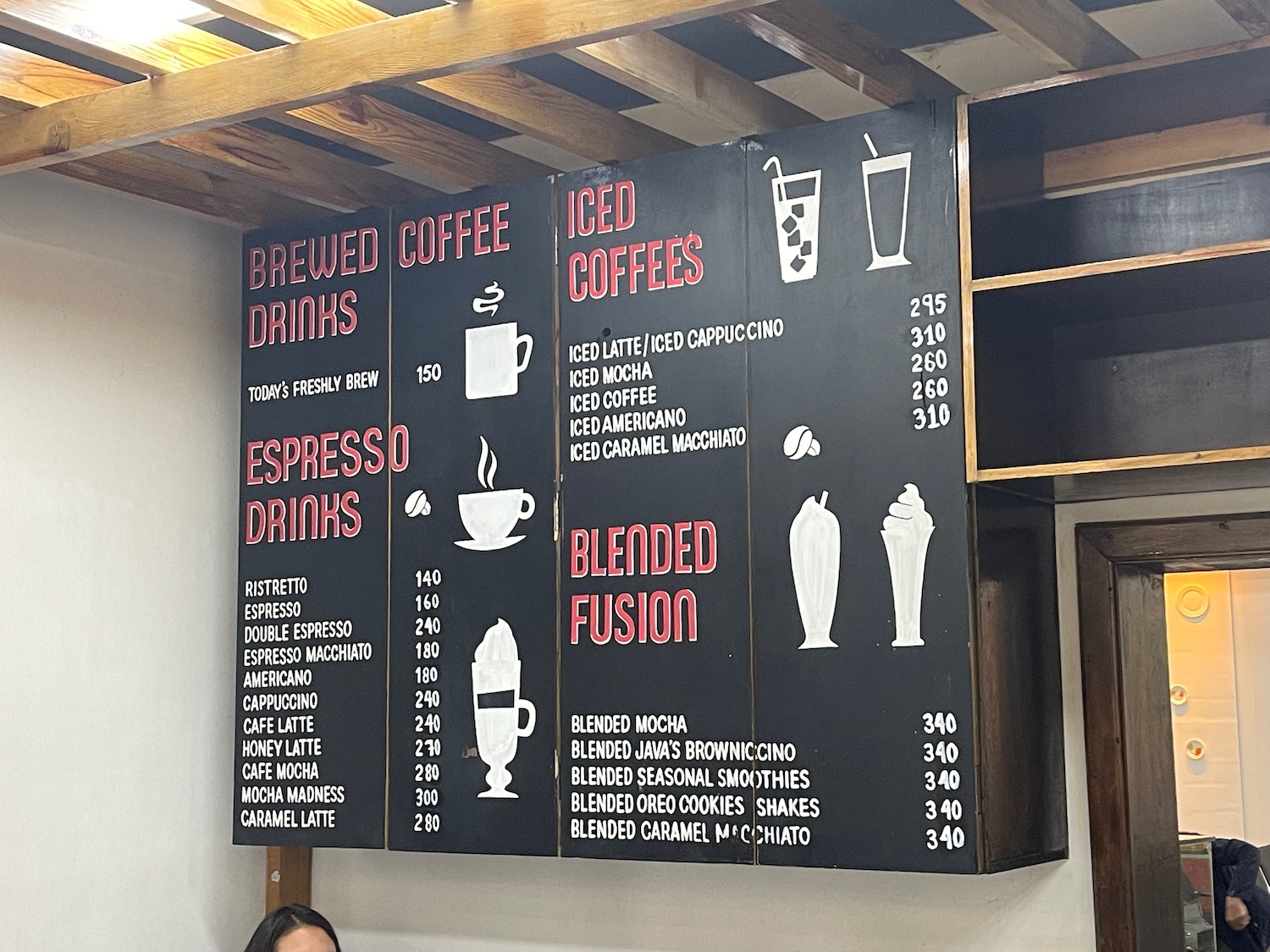 a woman sitting in front of a menu board