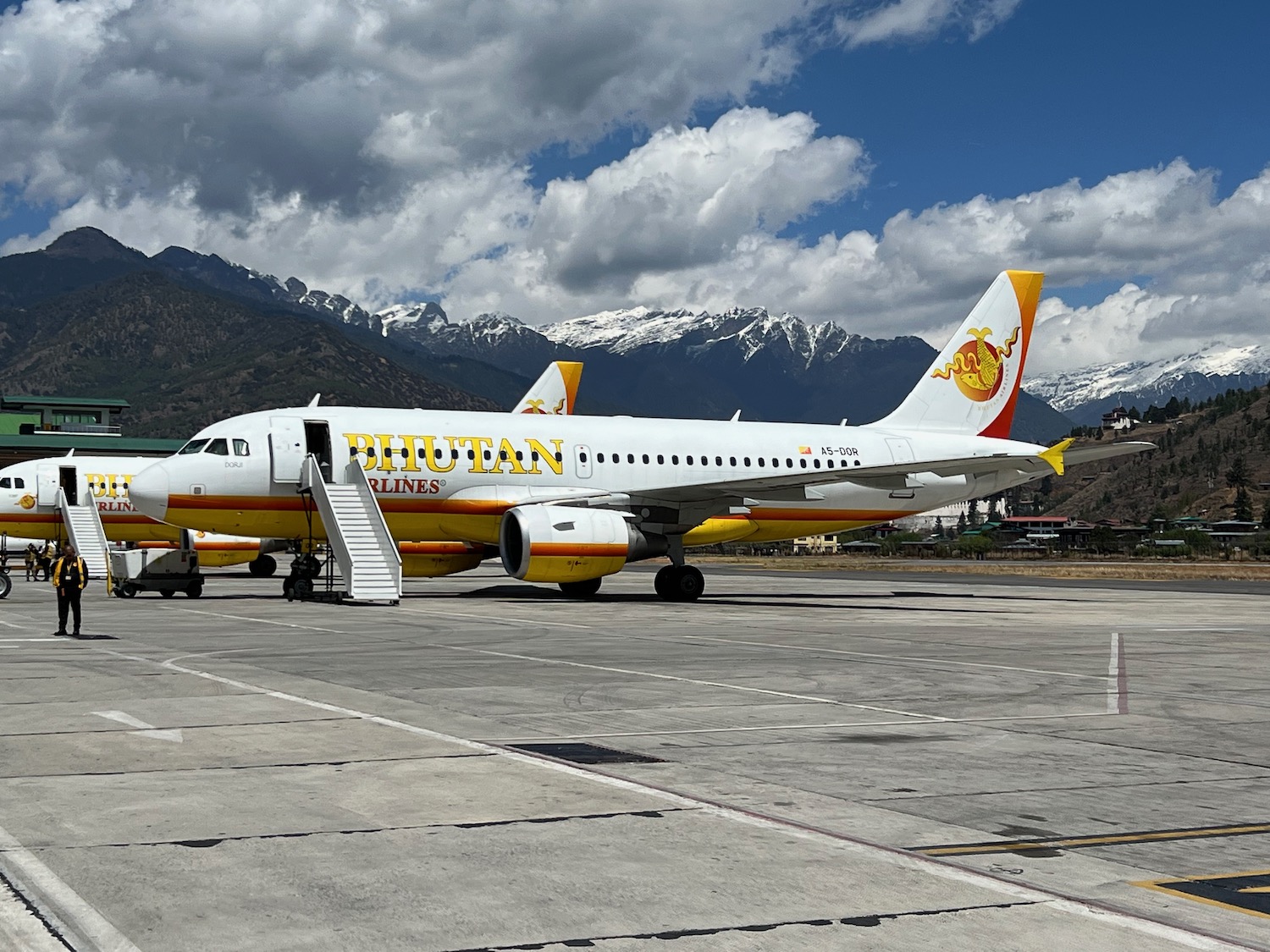 a white airplane on a runway with mountains in the background