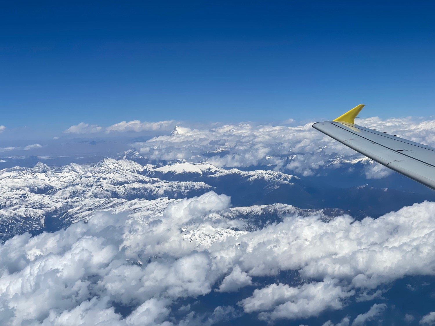 a wing of an airplane flying over clouds