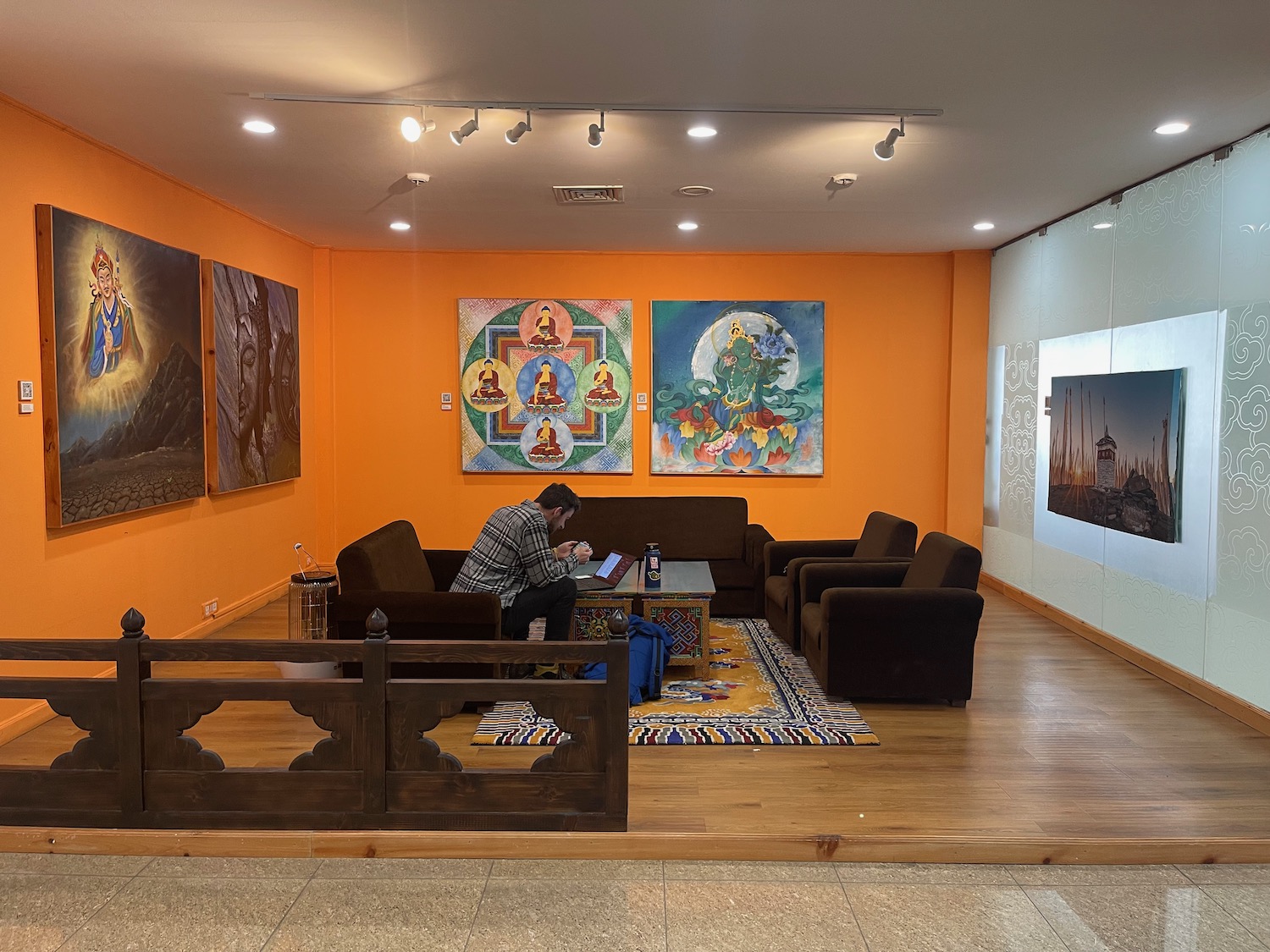 a man sitting on a couch in a room with paintings on the wall