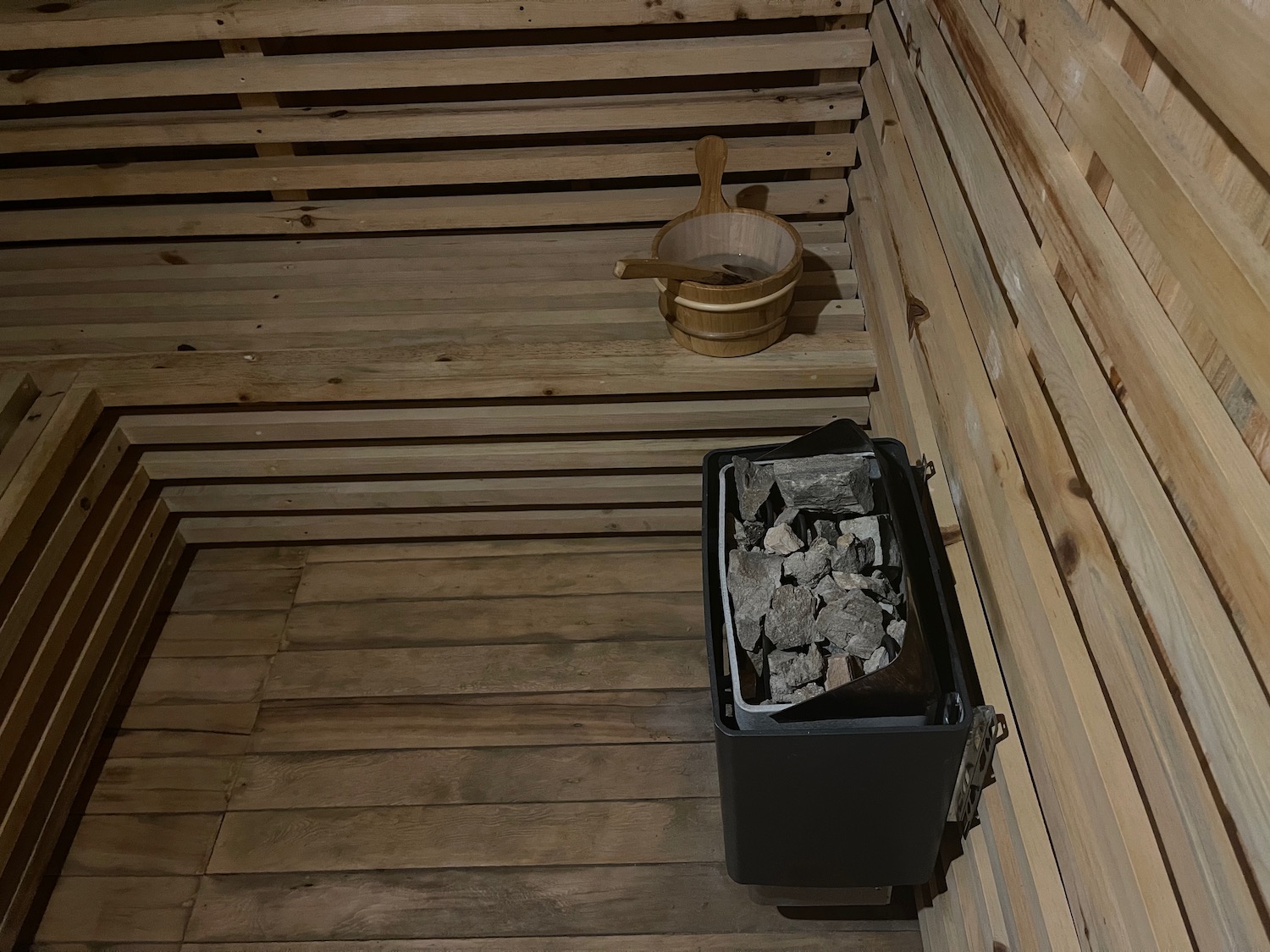 a wooden sauna with a bucket and a black container