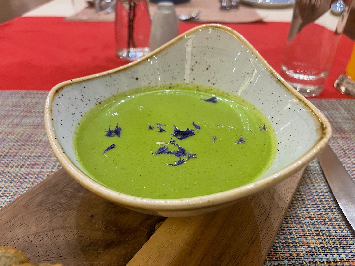 a bowl of green soup with blue flowers on top