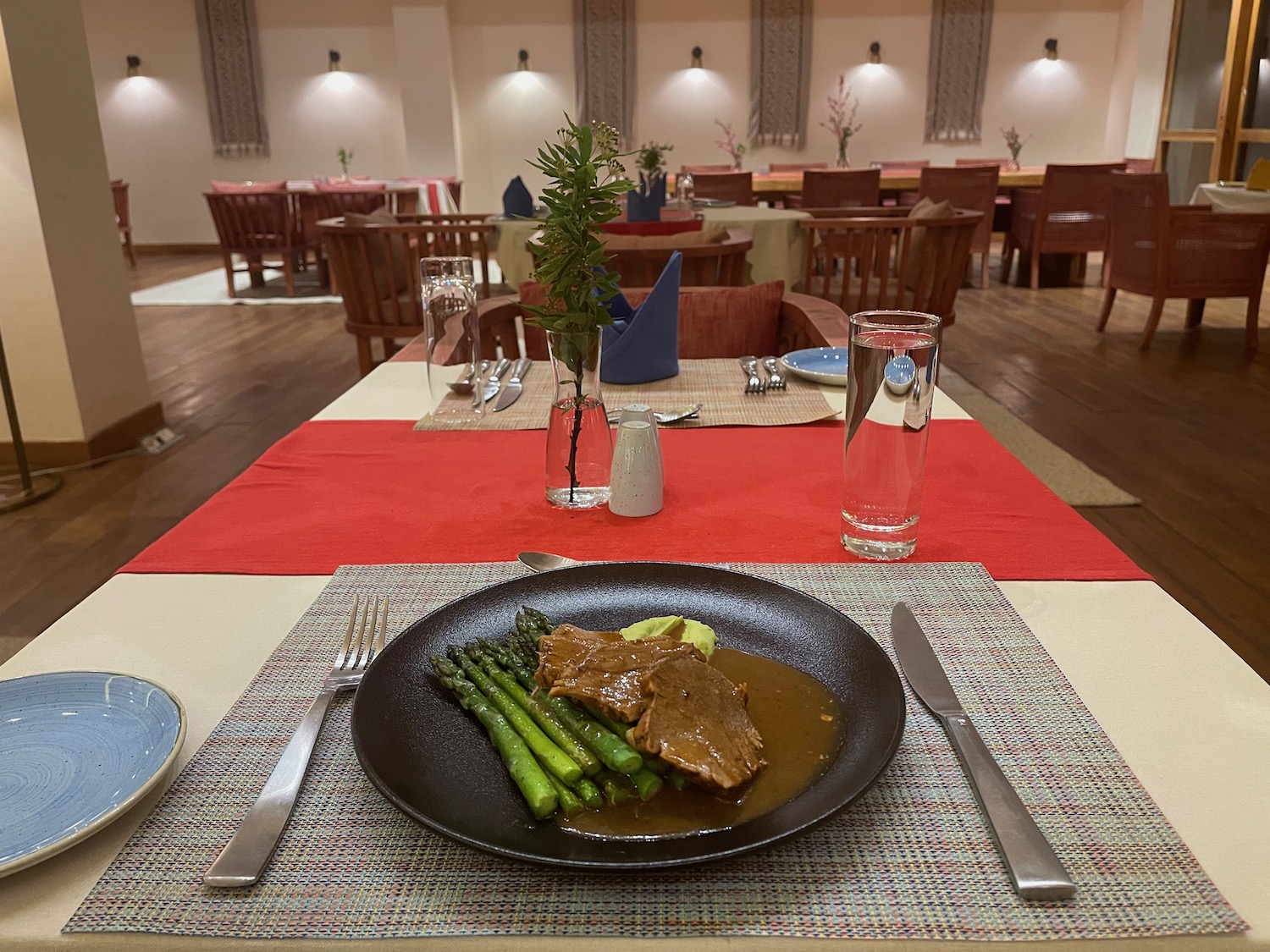 a plate of meat and asparagus on a table with a red place mat