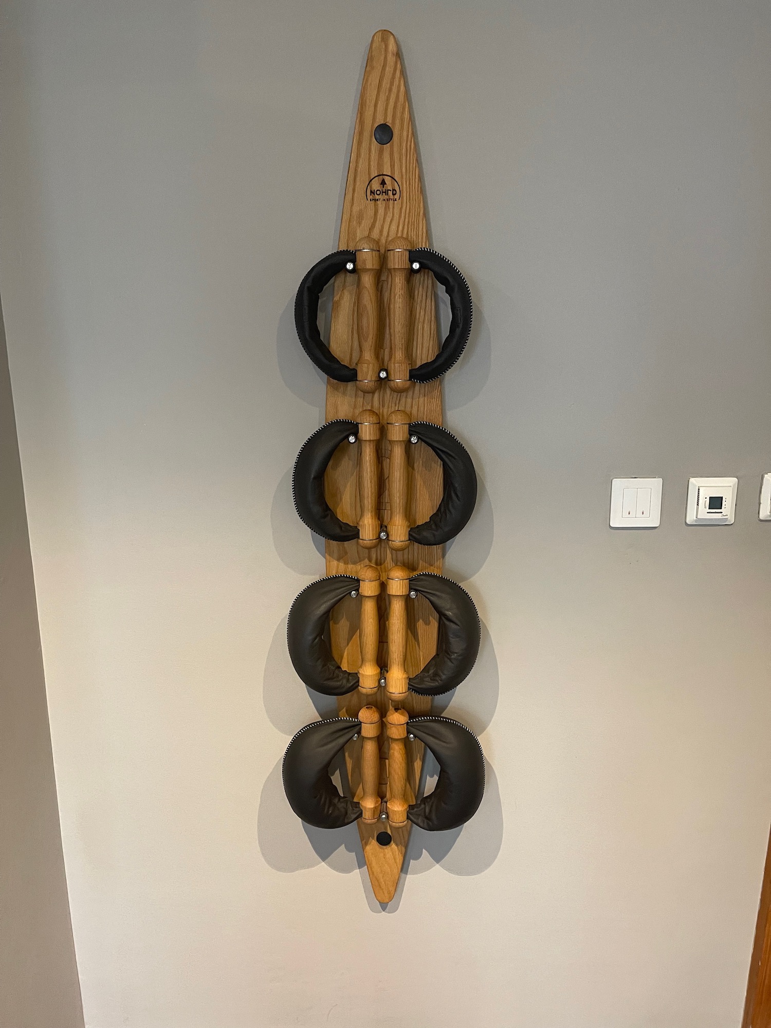 a wooden surfboard with black handles on a wall